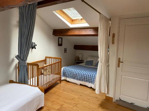 une chambre avec un berceau et un lit avec une lucarne dans l'établissement Maison à la montagne, à Sem