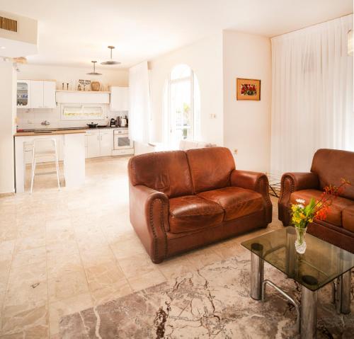 a living room with two brown leather couches and a table at Exclusive Jerusalem Villa in Giv‘ot Mordekhay