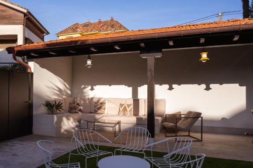 a patio with chairs and tables under a pergola at Apartamentos Las Indianas in Nueva de Llanes