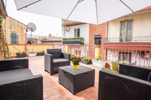 a patio with chairs and tables and an umbrella at Appartamento Georgiana in Taormina