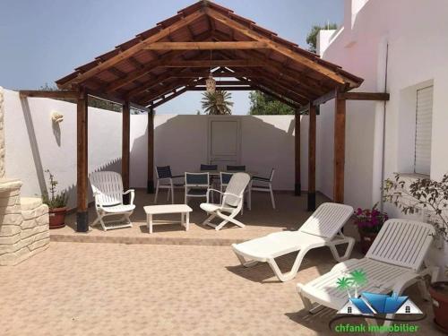 un patio con sillas blancas y un pabellón en Villa Bacha en Houmt El Souk