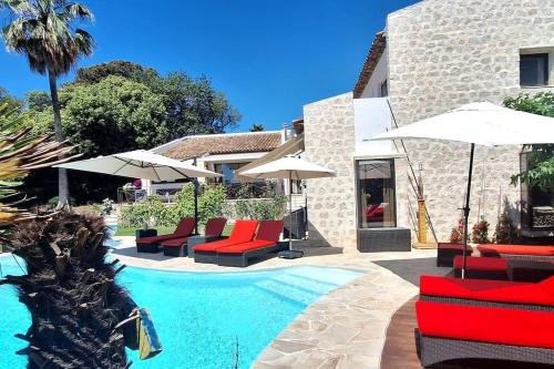 - une piscine avec des chaises et des parasols à côté d'un bâtiment dans l'établissement PRESTIGE PROPERTY WITH PANORAMIC SEA VIEW, à Vallauris