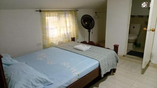 a bedroom with a bed and a fan and a bathroom at Deptos VILLA AURORA in Roldanillo