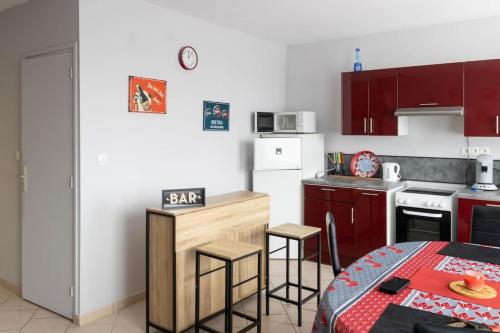 une cuisine avec des placards rouges et une table dans l'établissement L'hébergement du Faubourg Landrecies, à Landrecies