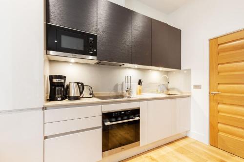 a kitchen with white cabinets and a microwave at Soho - Central London - CityApartmentStay in London