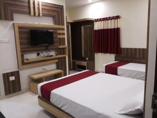 a bedroom with two beds and a flat screen tv at HOTEL R K RESIDENCY MUZAFFARPUR in Muzaffarpur