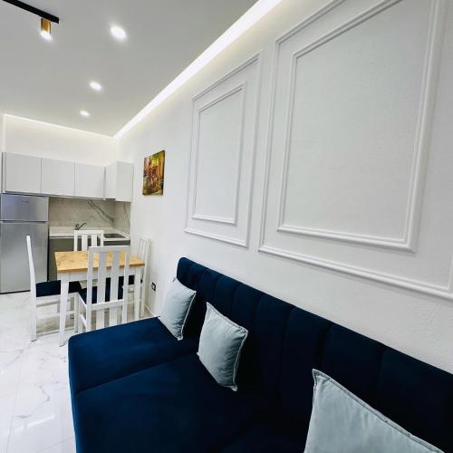 a living room with a blue couch and a kitchen at Apartments Oda Hotel in Velipojë