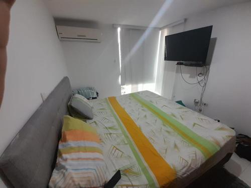 1 dormitorio con 1 cama y TV en la pared en APARTAHOTEL PALMETTO, en Neiva