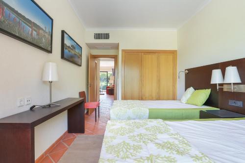 ヴィラモウラにあるF5 Vila Sol by Garveturのベッド2台とデスクが備わるホテルルームです。