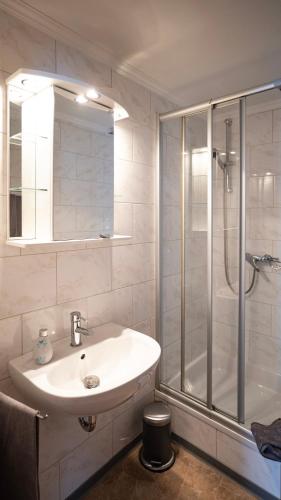 a white bathroom with a sink and a shower at Hotel Royal in Monschau