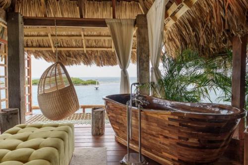 a bath tub in a thatched room with a view of the ocean at Overwater penthouse aruba in Savaneta