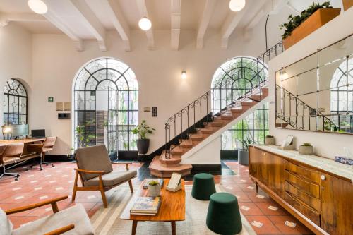 a lobby with a staircase and tables and chairs at Santa Casa by Tasman in Mexico City