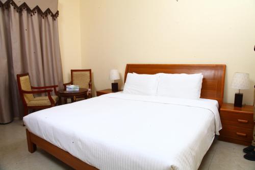 um quarto com uma grande cama branca e 2 cadeiras em Dream Palace Hotel em Ajman