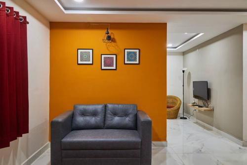 un sofá en una habitación con una pared de color naranja en Pent House 1BHk @WiproCircle, Near US Embassy, Gachibowli en Hyderabad