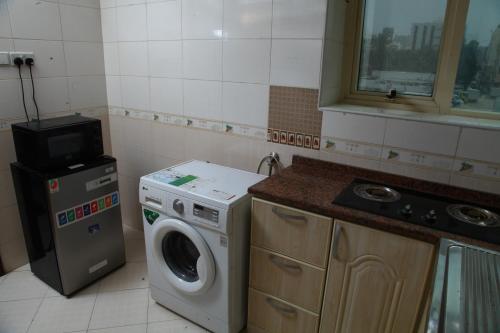 a kitchen with a washing machine and a microwave at Dream Palace Hotel in Ajman 