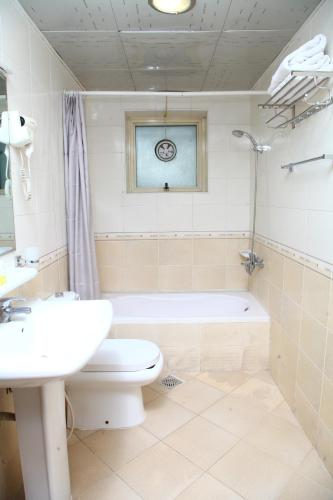 a bathroom with a toilet and a sink and a tub at Dream Palace Hotel in Ajman 