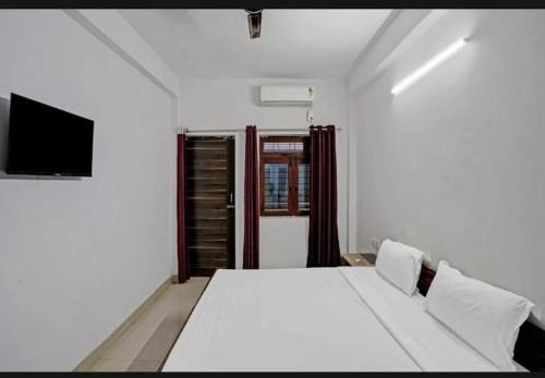 ノイダにあるHotel The Grand Shivaのベッドルーム(白いベッド1台、テレビ付)
