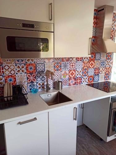 a kitchen with a sink and a tile wall at Ängelholm boende in Ängelholm