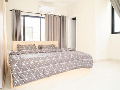 a bedroom with a bed with a gray comforter and a window at SERENE HAVEN RETREAT in Accra