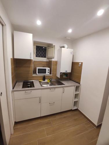 a kitchen with white cabinets and a sink and a microwave at Duchessa Ravaschieri bed and breakfast in Naples