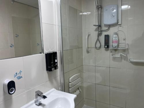 uma casa de banho branca com um chuveiro e um lavatório. em Charming 2-Bedroom in MANCHESTER em Manchester
