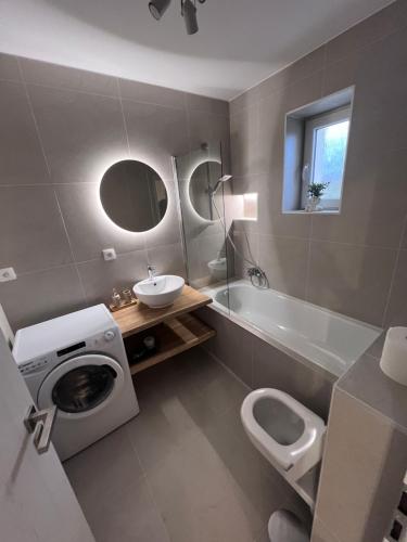 a bathroom with a toilet and a sink and a washing machine at Apartment ZANzi in Šamorín