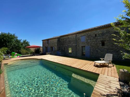 una piscina con terraza de madera y una casa en Clos Baroanni - Gîte Terra en Terraube