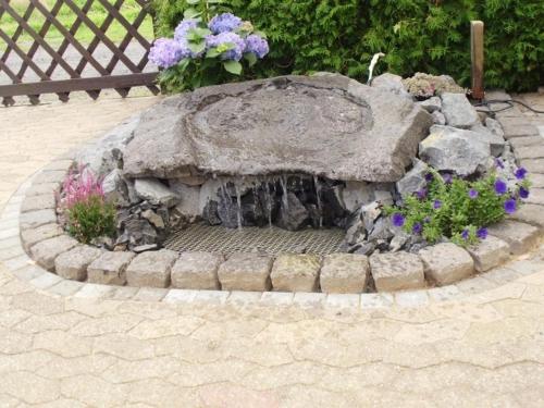 a stone fountain in a garden with flowers at Ferienhaus Wagner in Weiler