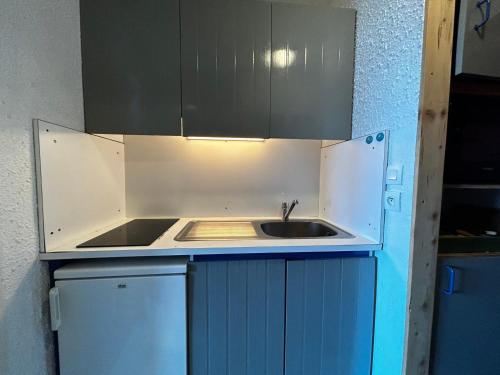 eine kleine Küche mit einem Waschbecken und blauen Schränken in der Unterkunft Studio Les Menuires, 1 pièce, 2 personnes - FR-1-452-264 in Les Menuires