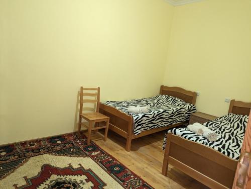 Pokój z 2 łóżkami, krzesłem i dywanem w obiekcie Sofia w mieście Wardzia
