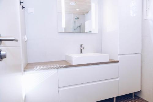 W białej łazience znajduje się umywalka i lustro. w obiekcie Villa Jumo Iniö w mieście Iniö