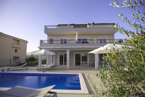 a house with a swimming pool in front of a building at Polo Villa & Suites in Podstrana