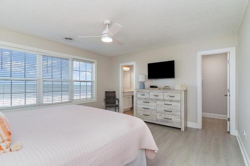 a white bedroom with a bed and a television at 311B - True Beachfront w/ Private Walkway and Pool in Myrtle Beach
