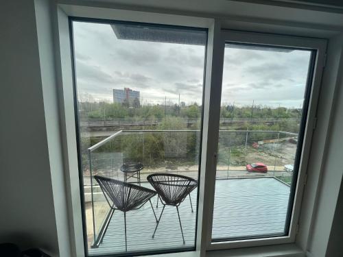 a window with two chairs sitting on a balcony at Manchester's Luxurious 3-Bed Haven with Balcony & Free Parking - Canal Views & Proximity to Manchester United in Manchester