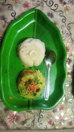 a green plate with food on it with a spoon at Anandi Nivas in Talavda