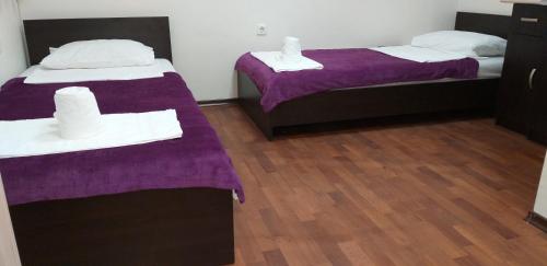 2 camas en una habitación con sábanas moradas y toallas blancas en Апартамент Поморие плажен комплекс, en Pomorie