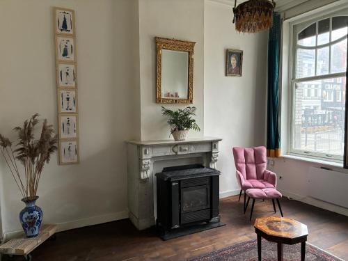 ein Wohnzimmer mit einem Kamin und einem rosa Stuhl in der Unterkunft Belle Epoque flat in the heart of Ostend in Ostende