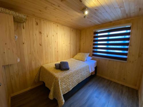 a bedroom with a bed in a wooden room at Cabañas Quina Nativa in Quinamávida