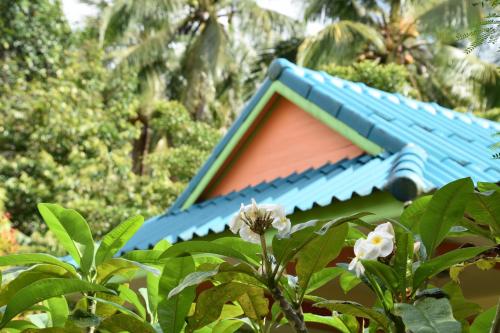a blue and orange house with trees in the background at Kama Siri Koh Kood in Ko Kood