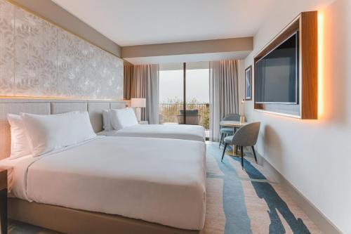 a hotel room with two beds and a flat screen tv at Legacy Hotel Cascais, Curio Collection By Hilton in Cascais