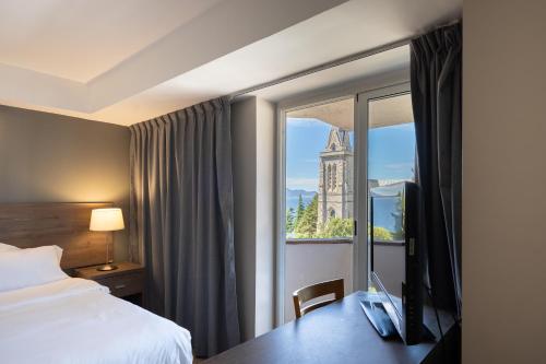 um quarto de hotel com uma cama e uma janela em Hotel Alt Interlaken em San Carlos de Bariloche