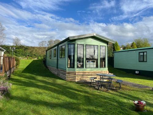 a green tiny house with a picnic table in a yard at Natland Caravan Park in Kendal