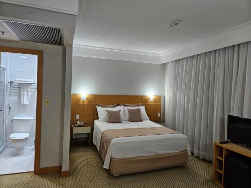 a hotel room with a bed and a television at Flat Hotel Slaviero Guarulhos in Guarulhos