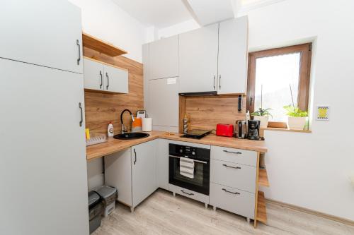 a small kitchen with white cabinets and a window at Cross Caraiman View 2 in Buşteni