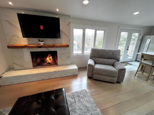 a living room with a fireplace with a tv and a chair at Waterfront Lakehouse Getaway in Clinton with HOT TUB in Clinton