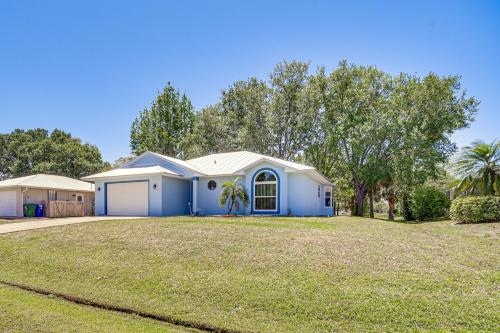 a house with a blue garage and a yard at Pet-Friendly Sebastian Home with Porch and Lake View! in Sebastian
