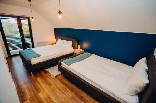 Un dormitorio con dos camas y una pared azul. en NorthSpot Cabin, en Horodnic de Sus
