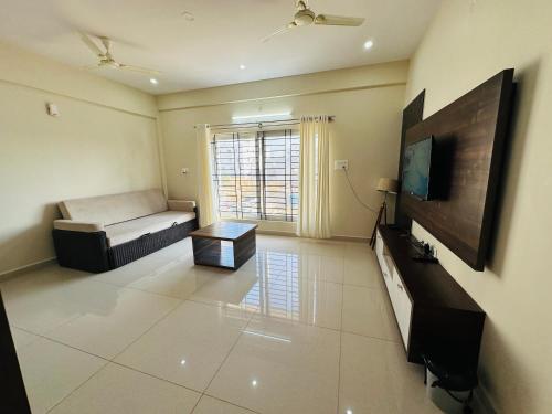 a living room with a bed and a flat screen tv at Oryx Residences - Luxury Serviced Apartments in Mysore