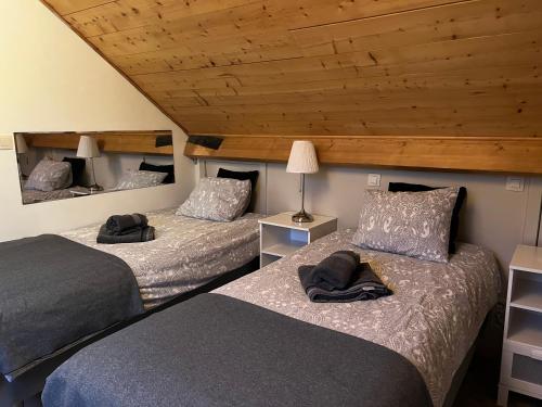two beds in a room with wooden ceilings at Dame Cerise in Wavre