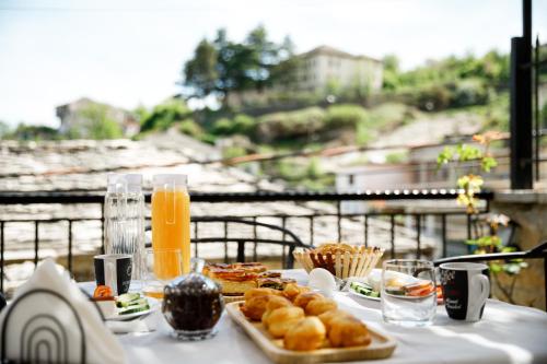 een tafel met eten en sinaasappelsap op een balkon bij Hotel Pashai in Gjirokastër